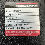Close-up of calibration label for the 1kg weight showing 2023 date and serial number.